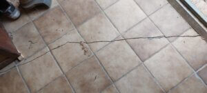 Fissure qui apparait tout le long d'un sol et qui a cassé les carreaux de carrelage